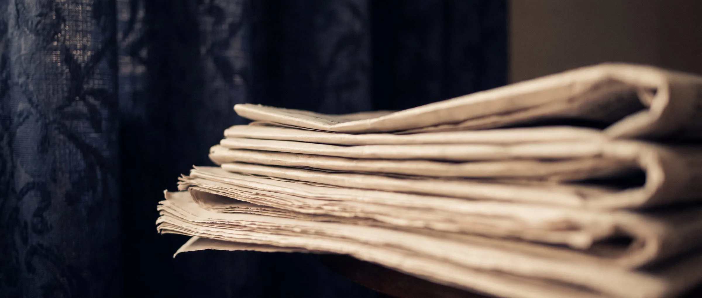 Folded broadsheet pages softly out of focus in warm light.