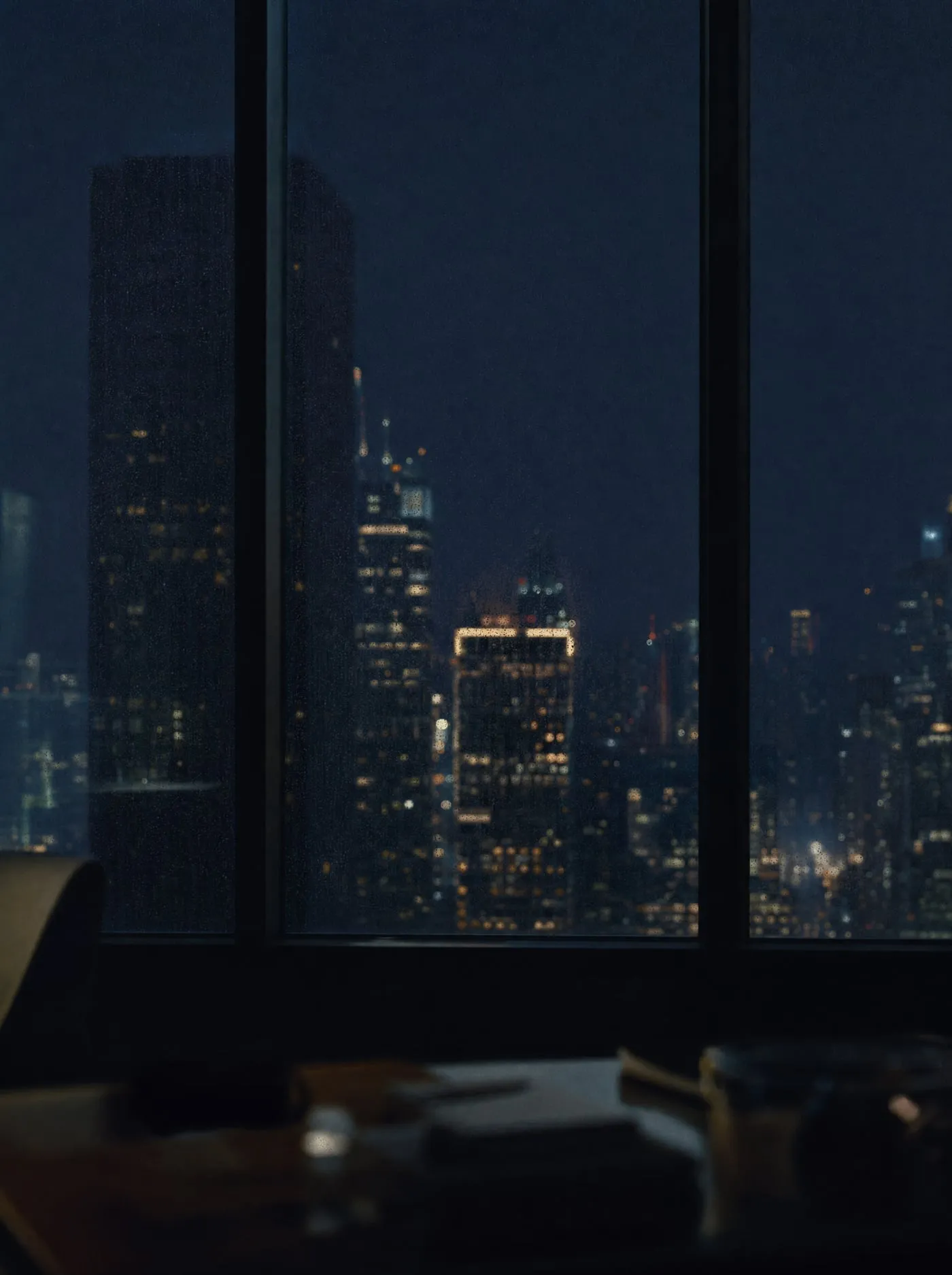 City lights at night through a rain-flecked office window.
